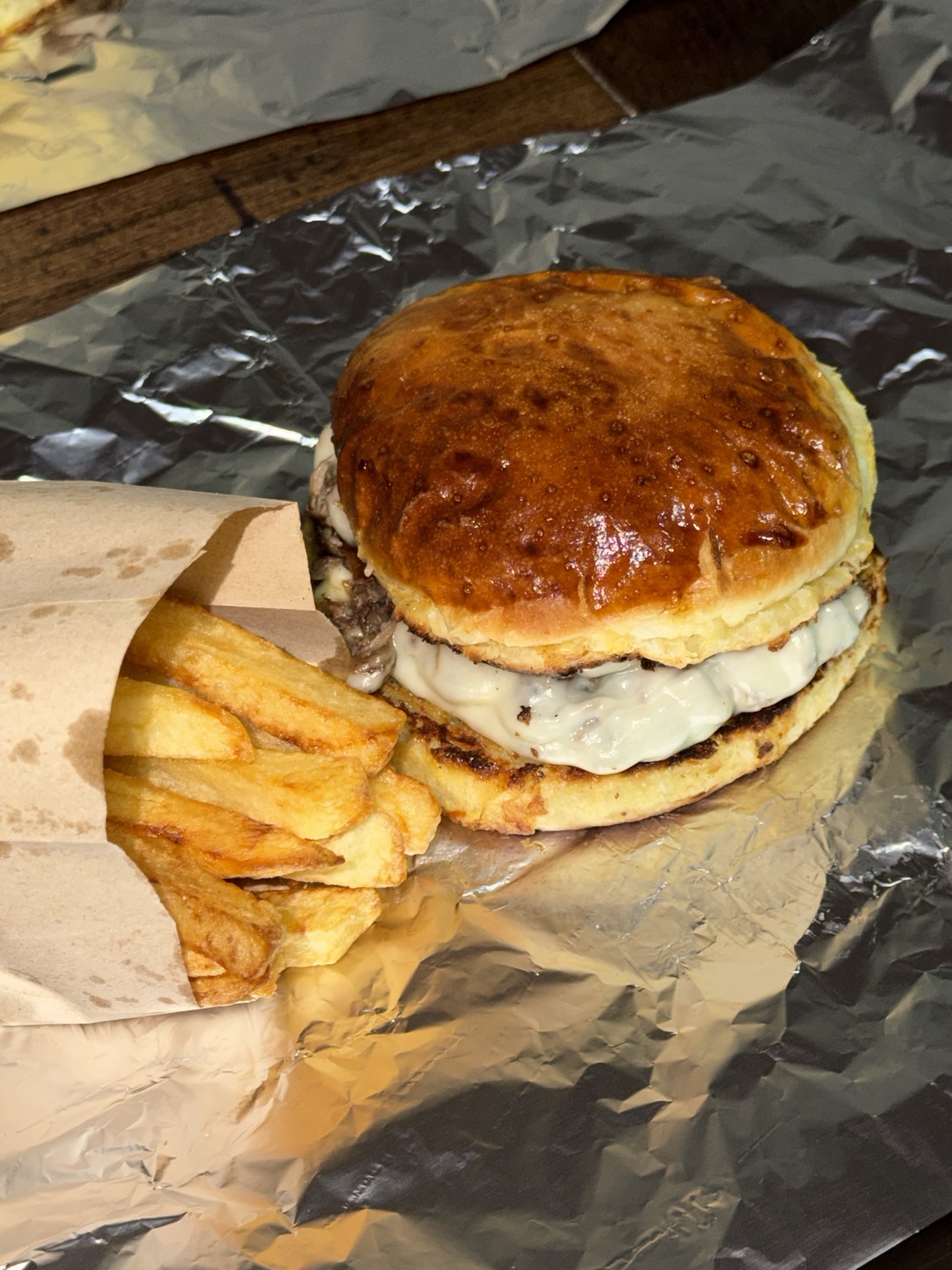 Hamburguesa completa con queso y papas en papel de aluminio